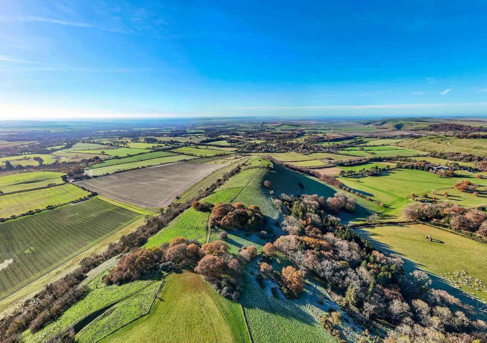 Aerial view of rolling English hills with the coastline in the distance